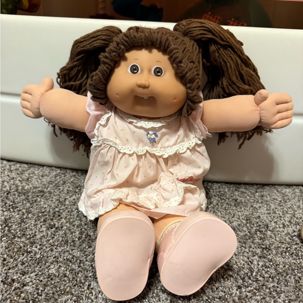 Vintage Cabbage Patch kid with brown pigtails, dimples, and a tooth